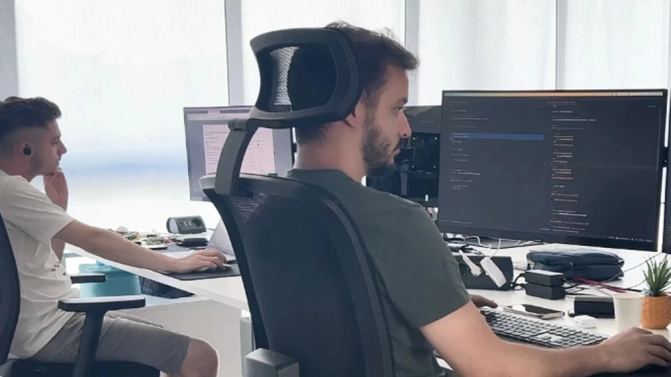 Due sviluppatori di dotenv alle loro scrivanie, uno davanti a un monitor con il codice aperto
